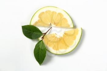 two slices of green grapefruit and leaves on white background