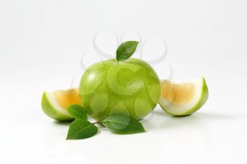 whole and sliced green grapefruit on white background