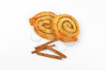 sweet cinnamon rolls and cinnamon sticks on white background