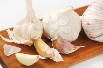 Fresh garlic bulbs and cloves on wooden cutting board