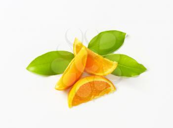 Fresh orange wedges and leaves on white background