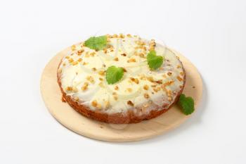 Carrot cake with cream cheese icing topped with chopped walnuts