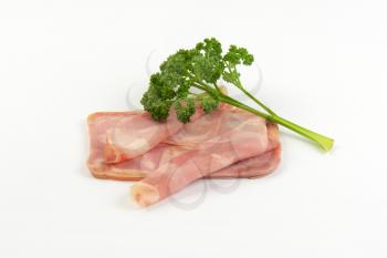 slices of pork ham with parsley on white background
