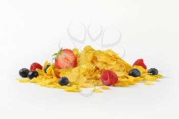 pile of corn flakes with berry fruits on white background