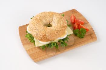 bagel sandwich with eggs and cheese on wooden cutting board