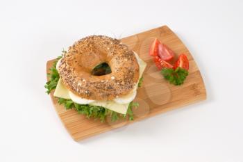 bagel sandwich with eggs and cheese on wooden cutting board