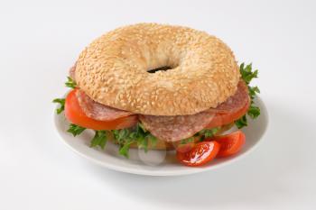 bagel sandwich with salami on white plate
