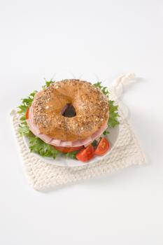 bagel sandwich with ham on white plate