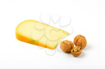slice of gouda cheese with walnuts on white background