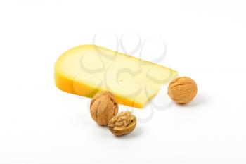 slice of gouda cheese with walnuts on white background