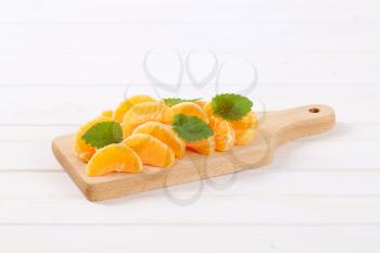 pile of fresh tangerine slices on wooden cutting board