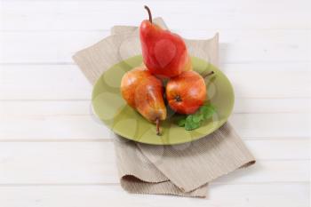 plate of ripe red pears on white background