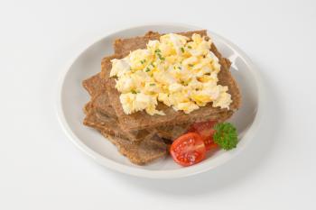 slices of fitness bread with scrambled eggs on white plate