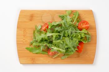 arugula and tomato salad on wooden cutting board