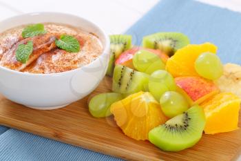 fresh fruit salad with cinnamon yogurt on wooden cutting board - close up