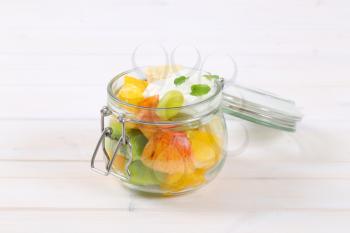 jar of fresh fruit salad with white yogurt on white background