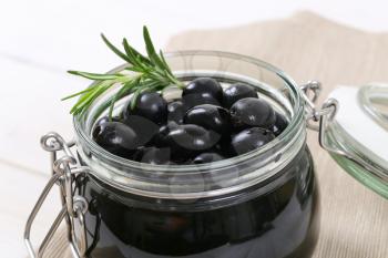 jar of black olives with fresh rosemary - close up
