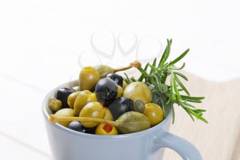 cup of pickled olives, capers and caper berries - close up