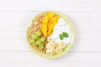 plate of muesli with white yogurt and fresh fruit on white background