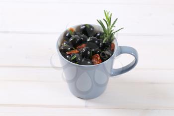 cup of black olives with dried tomatoes on white background
