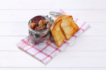 jar of baked beetroot and garlic with toasted bread on checkered dishtowel