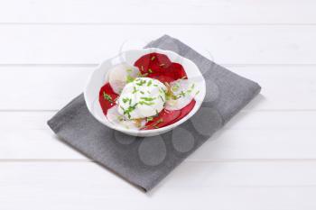 bowl of thin beetroot and white radish slices with yogurt