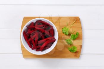 bowl of beetroot strips on wooden cutting board
