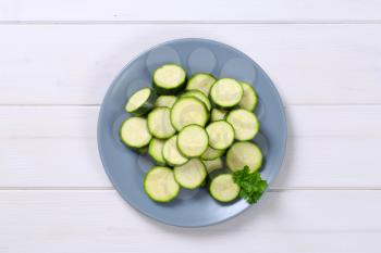 plate of green zucchini slices on white wooden background