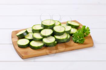 pile of green zucchini slices on wooden cutting board