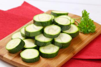 pile of green zucchini slices on wooden cutting board - close up
