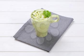 cup of raw zucchini noodles on grey place mat
