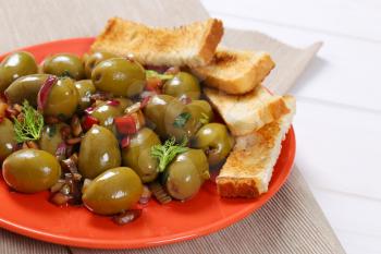 plate of marinated green olives with toast - close up