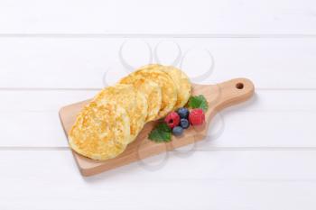 fresh american pancakes with raspberries and blueberries on wooden cutting board