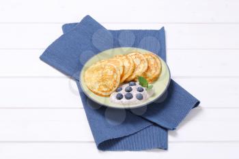 plate of american pancakes with yogurt and fresh blueberries on blue place mat