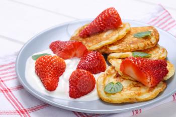 plate of american pancakes with white yogurt and fresh strawberries on checkered dishtowel - close up