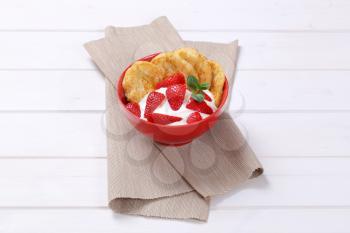 bowl of american pancakes with white yogurt and fresh strawberries on beige place mat