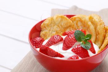bowl of american pancakes with white yogurt and fresh strawberries on beige place mat - close up