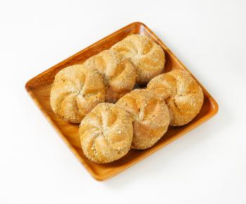 six whole wheat bulkie rolls on square wooden plate
