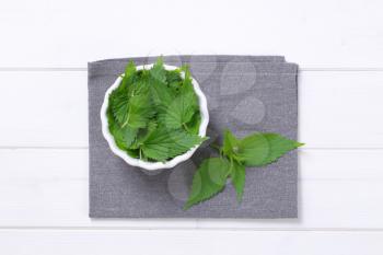 bowl of fresh nettle leaves on grey place mat