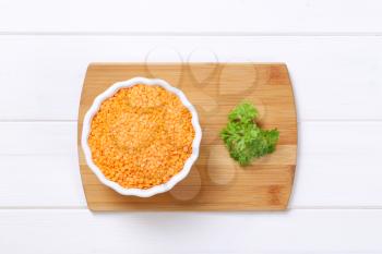 bowl of peeled red lentils on wooden cutting board