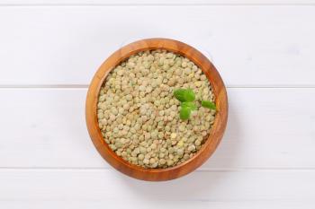 bowl of dry brown lentils on white wooden background