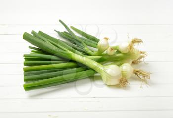 bunch of spring onion on white wooden background