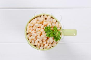 cup of canned white beans on white wooden background
