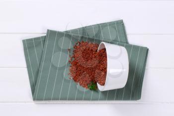 bowl of red rice spilt out on grey place mat