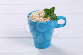 cup of puffed buckwheat on white wooden background