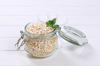jar of puffed buckwheat on white wooden background