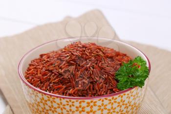 bowl of red rice on beige place mat - close up