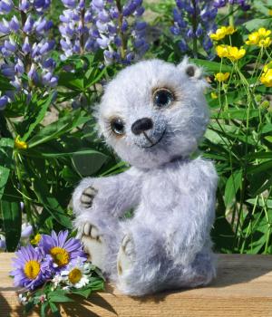 Handmade, the sewed toy: teddy-bear Chupa on a little board among flowers lupine and buttercups