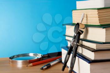 pen, big pile of books and magnifying glass on wood table