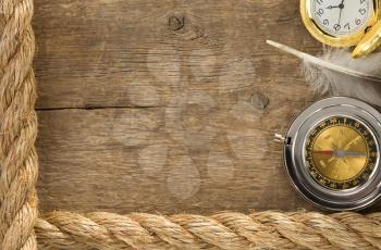 ship ropes and compass with feather at old wooden background